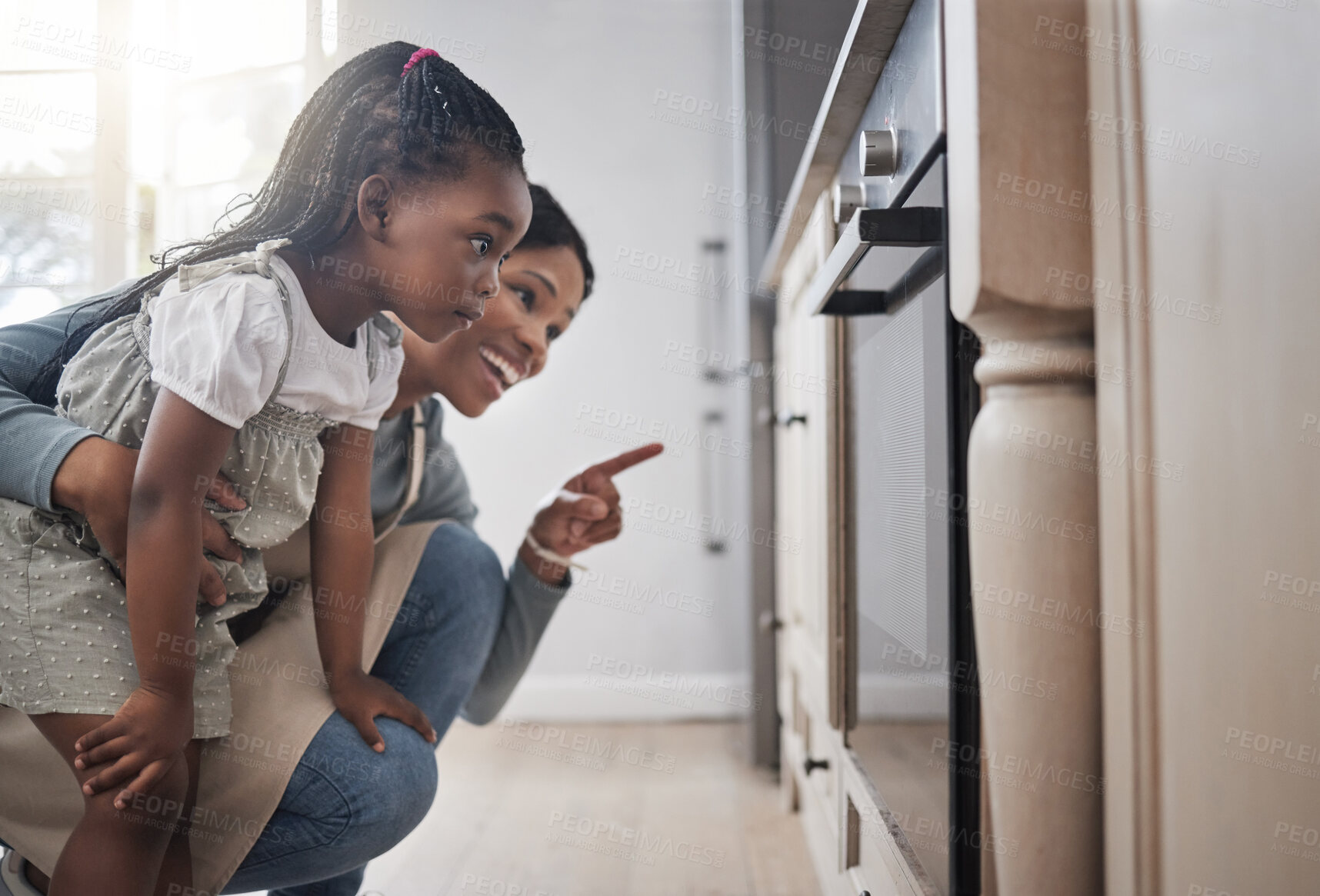 Buy stock photo Shot of a little girl and her mother sitting in front of the oven