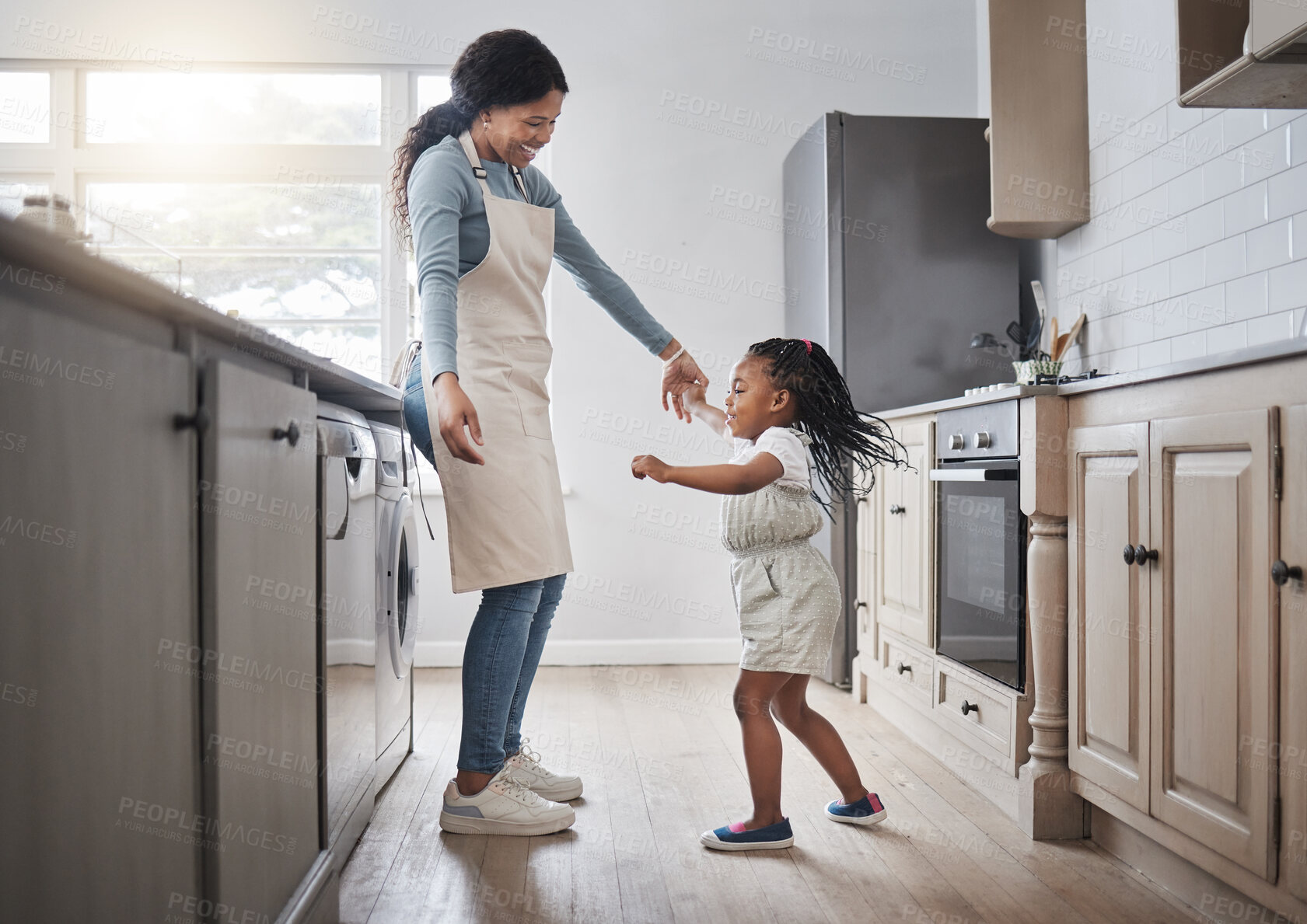 Buy stock photo Shot of a little girl and her mother dancing in the kitchen at home