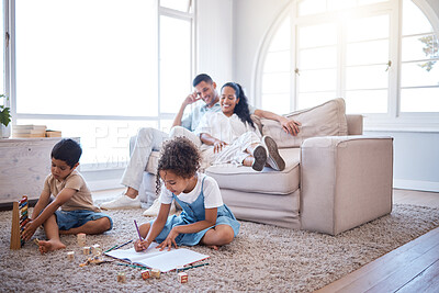 Buy stock photo Shot of two little siblings playing with toys and writing in a book while their parents are relaxing on a safe in the lounge at home