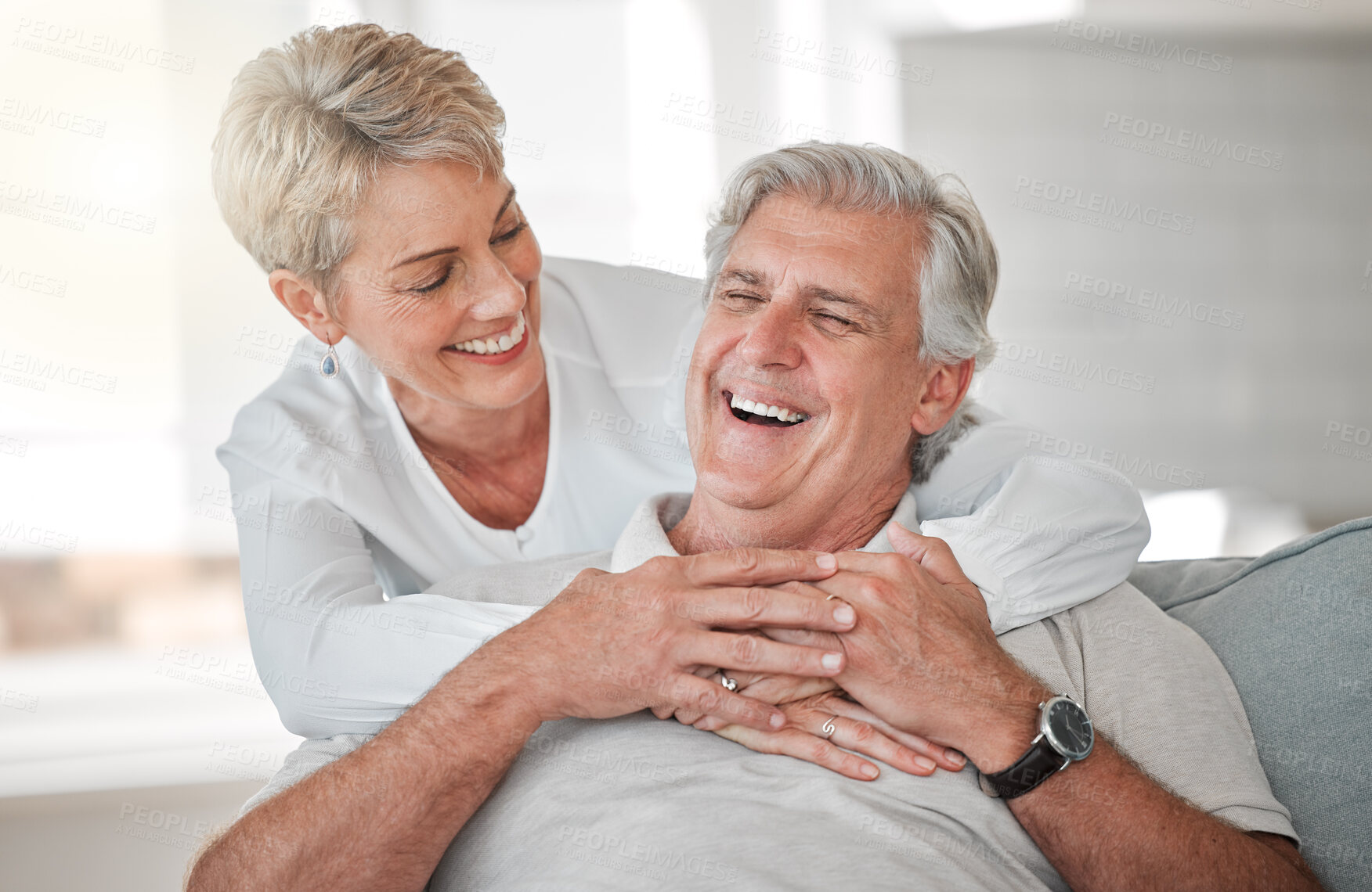 Buy stock photo Hug, senior couple and laughing on couch with love, connection and bonding together in home. House, woman and man on sofa in retirement, commitment and security and embrace support in marriage