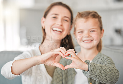 Buy stock photo Shot of a mother and daughter making a heart sign with their hands at home