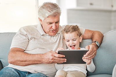 Buy stock photo Shot of an adorable little girl using a digital tablet while sitting at home with her grandfather