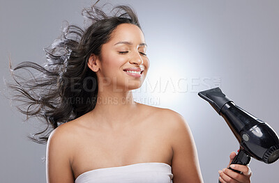 Buy stock photo Studio shot of a beautiful young woman blowdrying her hair