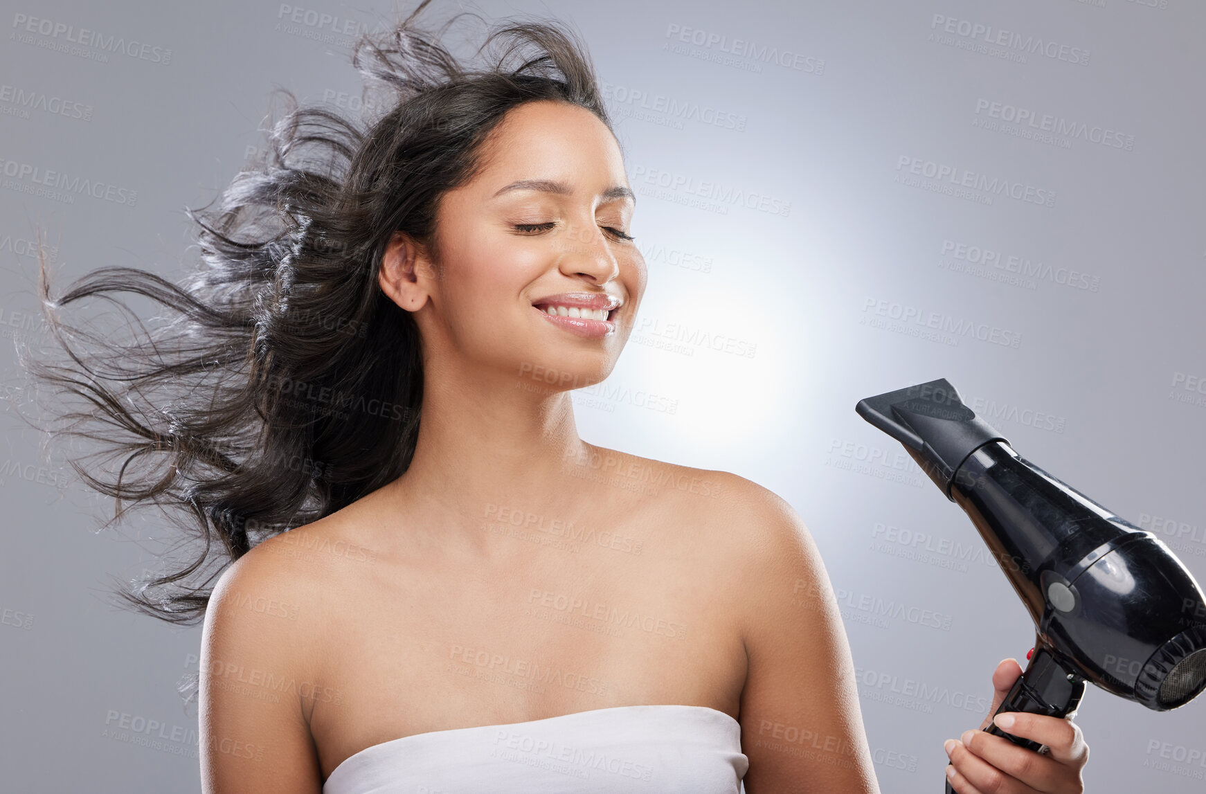 Buy stock photo Studio shot of a beautiful young woman blowdrying her hair