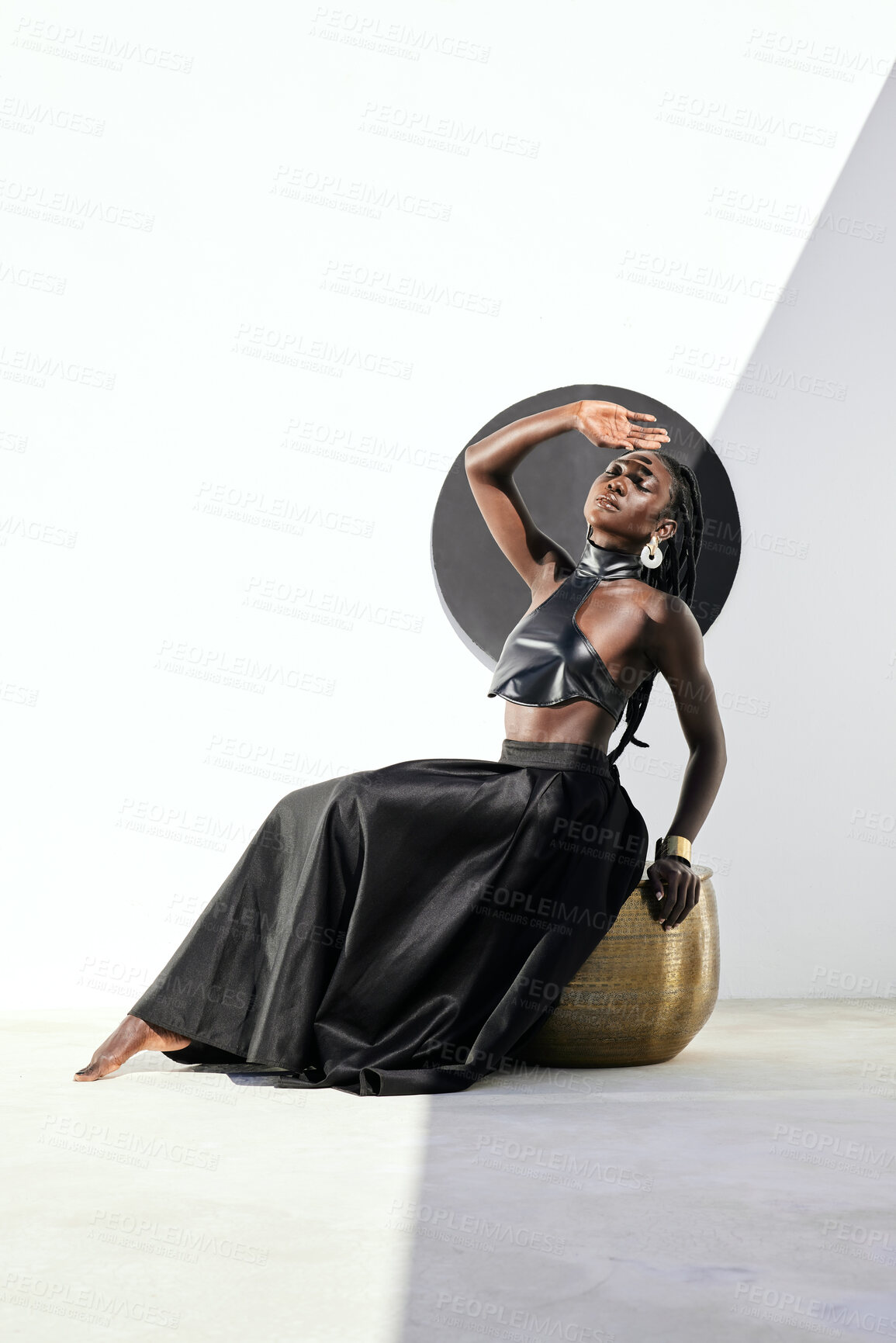 Buy stock photo Shot of an attractive young woman posing in a black outfit against a wall with a circle on it