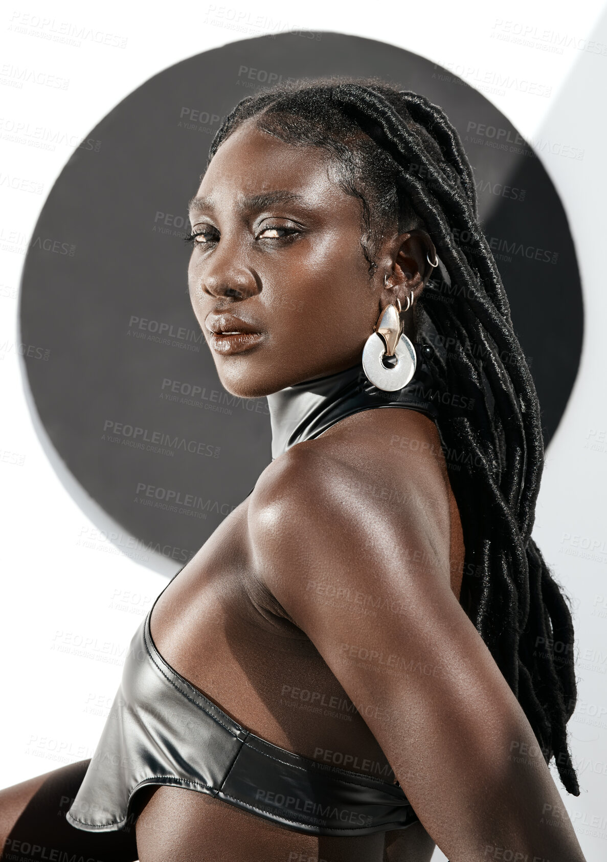 Buy stock photo Shot of an attractive young woman posing in a black outfit against a wall with a circle on it