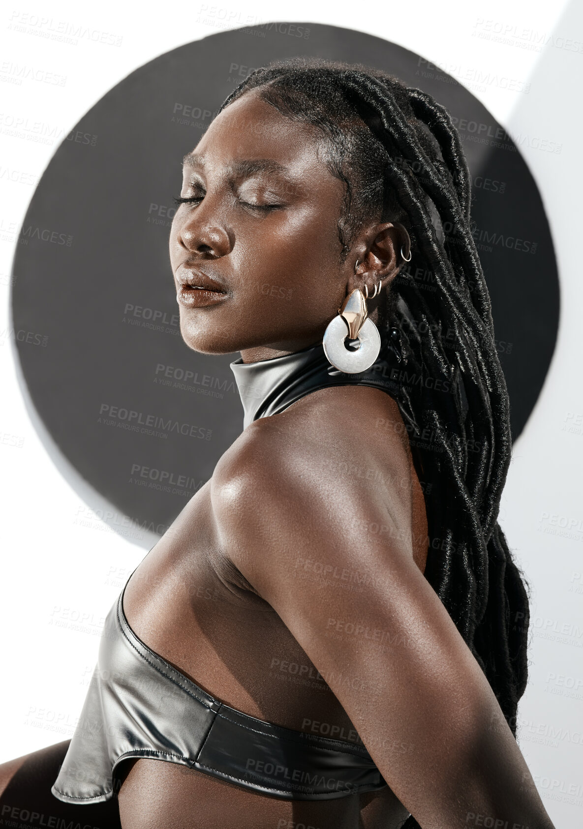 Buy stock photo Shot of an attractive young woman posing in a black outfit against a wall with a circle on it