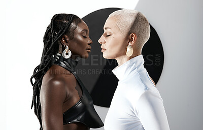 Buy stock photo Shot of two attractive young women posing against a wall with a black circle on it