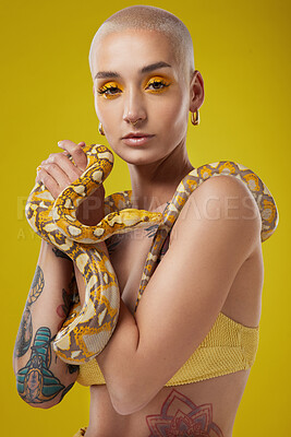 Buy stock photo Shot of a fashionable woman holding a snake while modelling a yellow concept