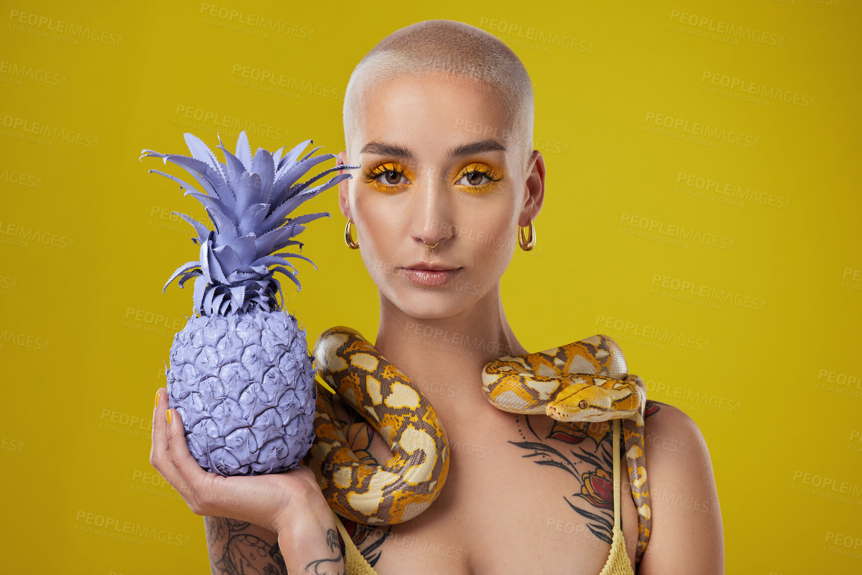 Buy stock photo Shot shot of a woman holding a painted pineapple while posing with a snake around her neck