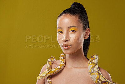 Buy stock photo Shot of a young woman posing with a snake around her neck against a yellow background