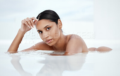 Buy stock photo Shot of a beautiful young woman lying nude in shallow water