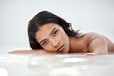 Buy stock photo Shot of a beautiful young woman lying in shallow water