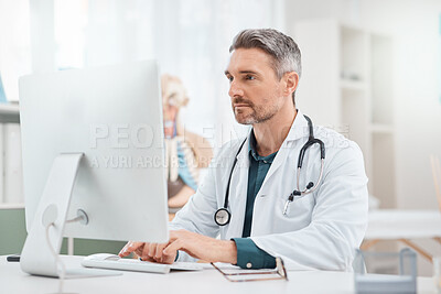 Buy stock photo Shot of a mature doctor working on a computer in a medical office