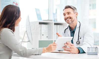 Buy stock photo Shot of a mature doctor using a digital tablet during a consultation with a patient in a medical office
