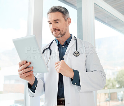 Buy stock photo Shot of a mature doctor using a tablet in a office