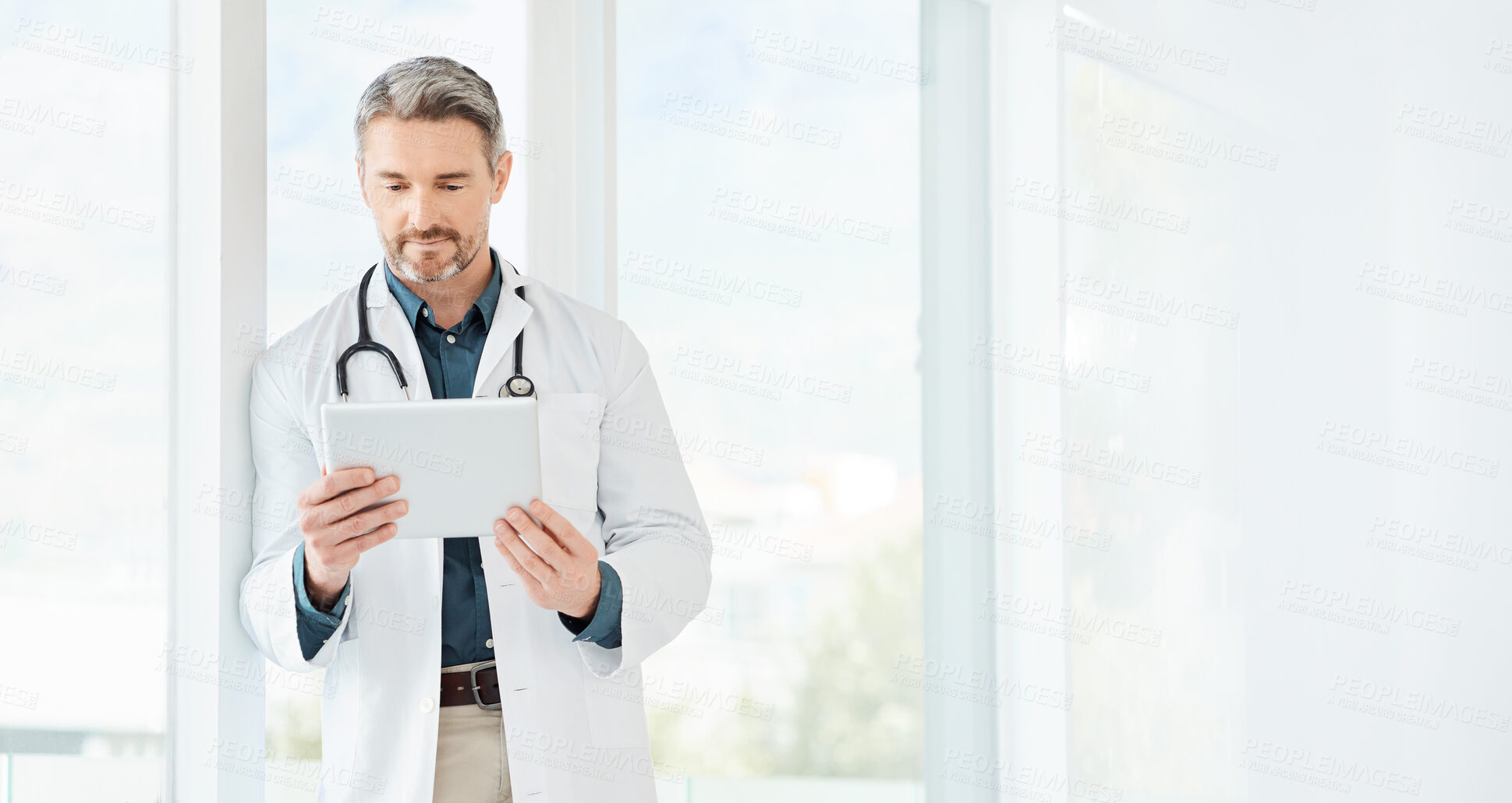 Buy stock photo Shot of a mature doctor using a tablet in a office