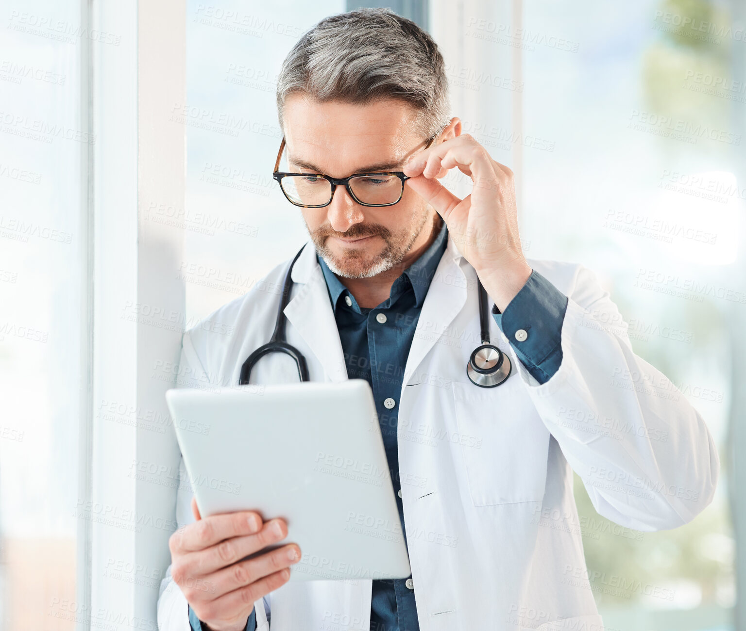 Buy stock photo Shot of a mature doctor using a tablet in a office