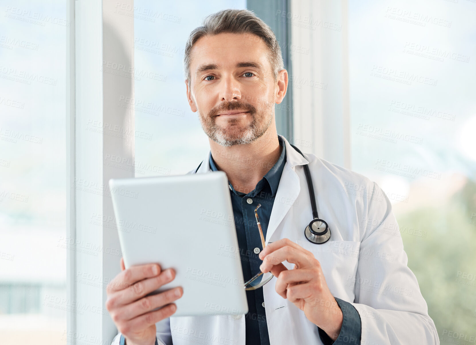 Buy stock photo Shot of a mature doctor using a tablet in a office