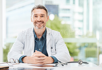 Buy stock photo Shot of a senior doctor sitting alone in his clinic
