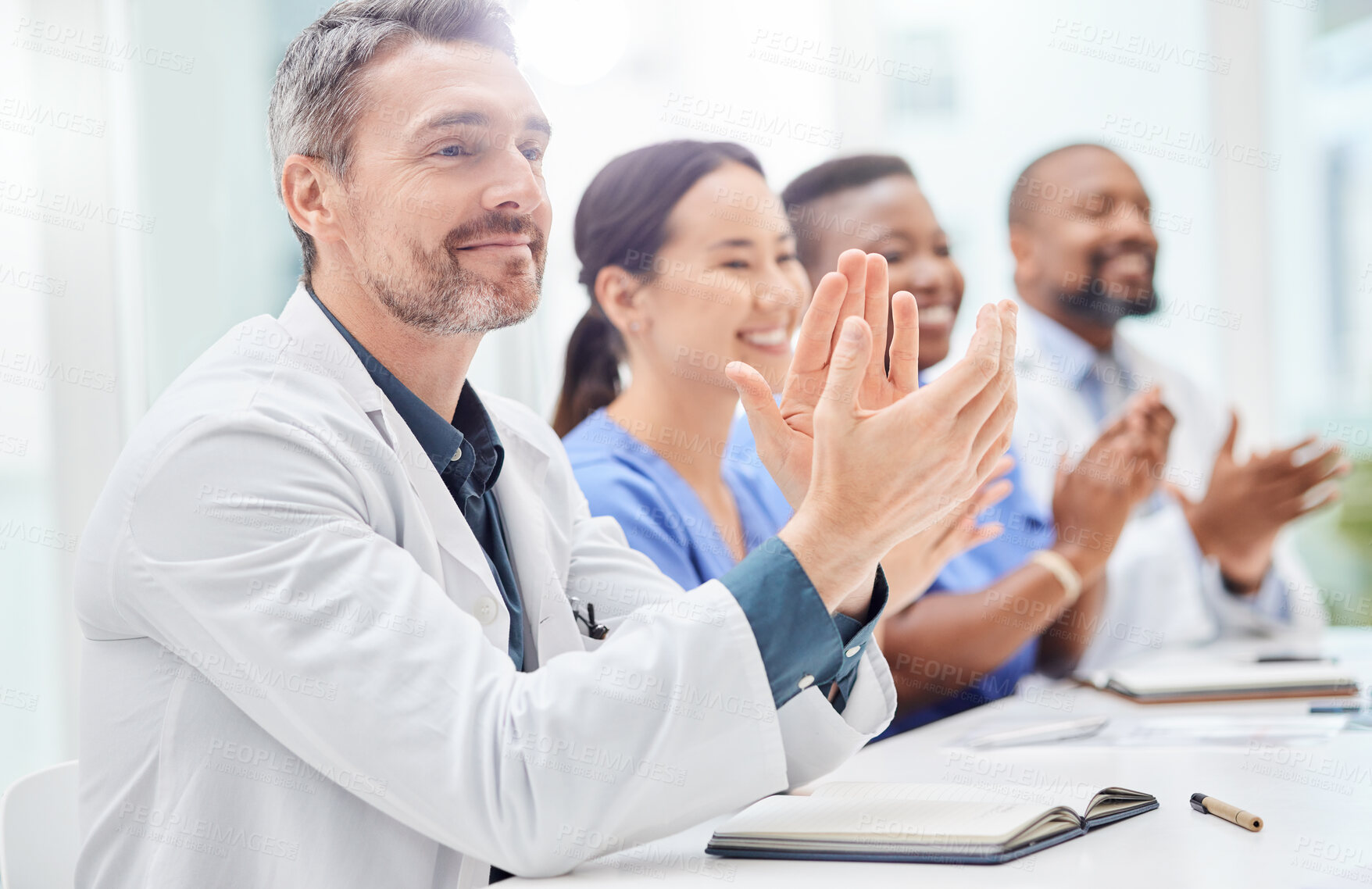 Buy stock photo Shot of a doctor sitting alongside his colleagues during a meeting in a hospital boardroom