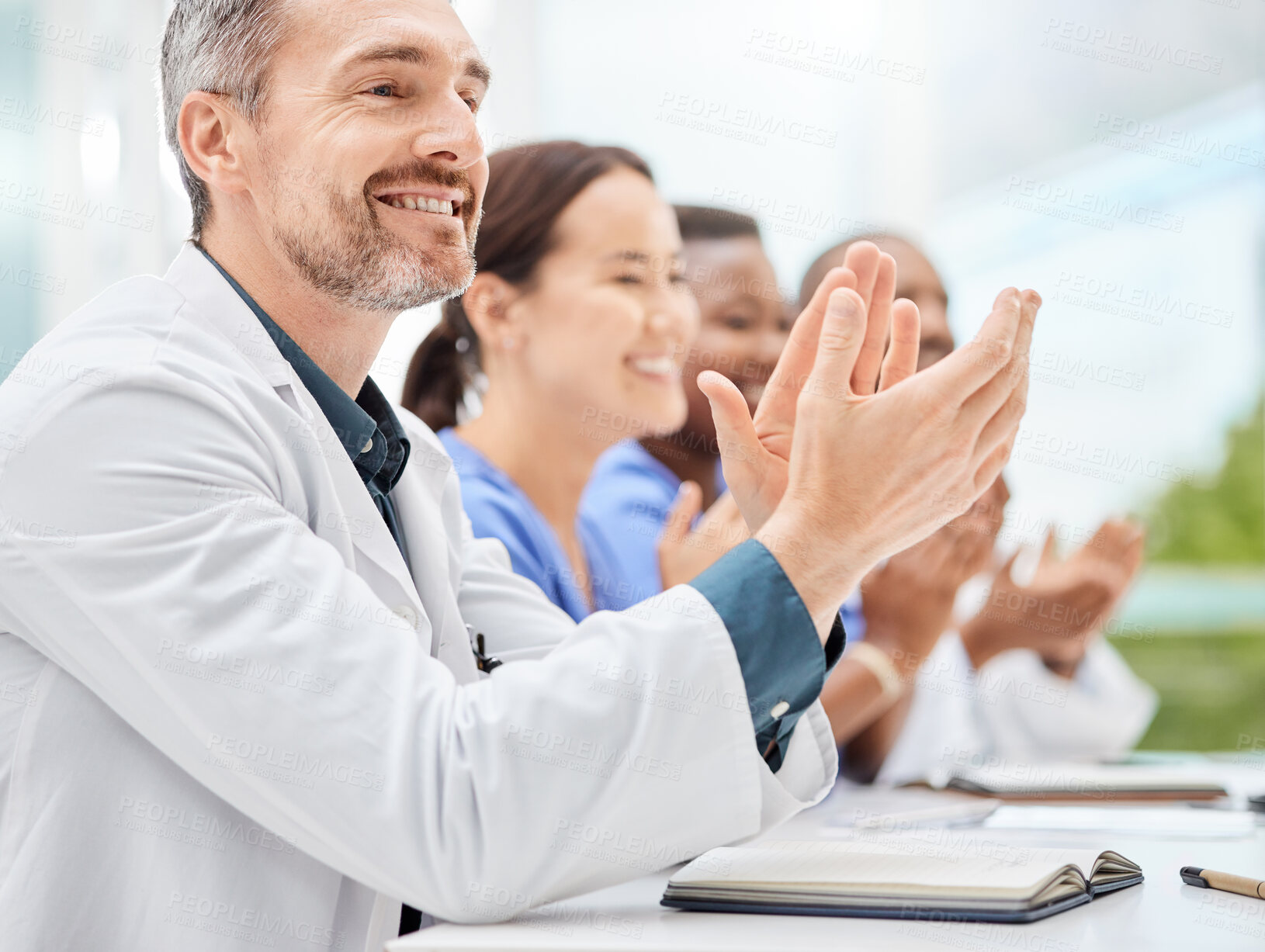 Buy stock photo Shot of a doctor sitting alongside his colleagues during a meeting in a hospital boardroom