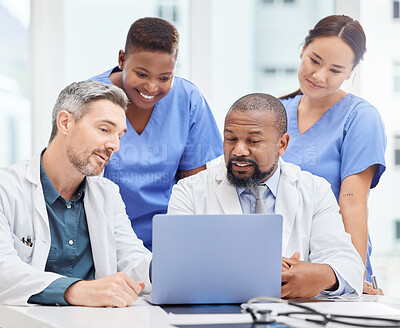 Buy stock photo Shot of a group of young doctors looking at a laptop during a meeting in the hospital boardroom