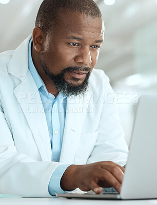 Buy stock photo Shot of a handsome mature scientist sitting alone in his laboratory and using his laptop