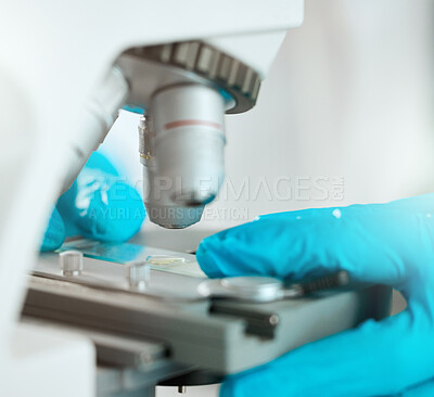 Buy stock photo Cropped shot of an unrecognisable scientist using a microscope to analyse a sample in the laboratory