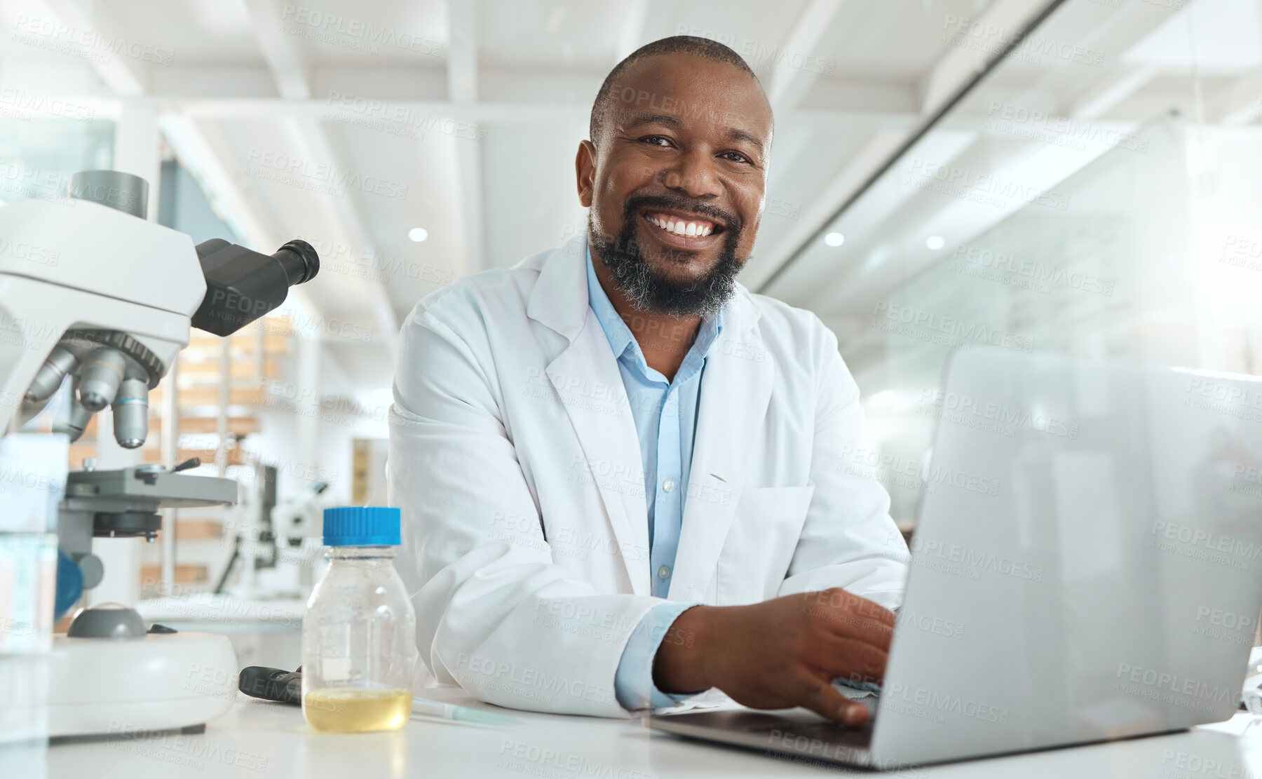 Buy stock photo Shot of a handsome mature scientist sitting alone in his laboratory and using his laptop