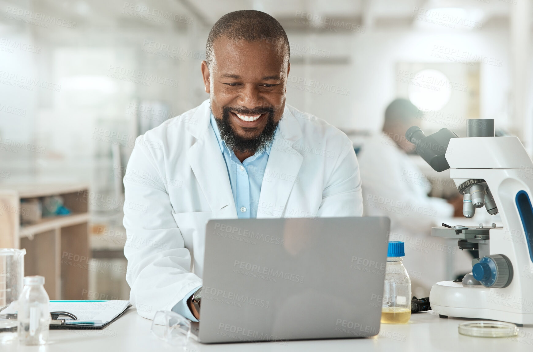 Buy stock photo Shot of a handsome mature scientist sitting alone in his laboratory and using his laptop