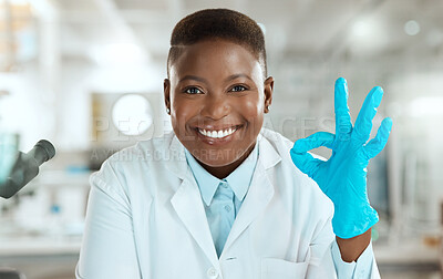 Buy stock photo Shot of an attractive young scientist sitting alone in her laboratory and making an okay sign