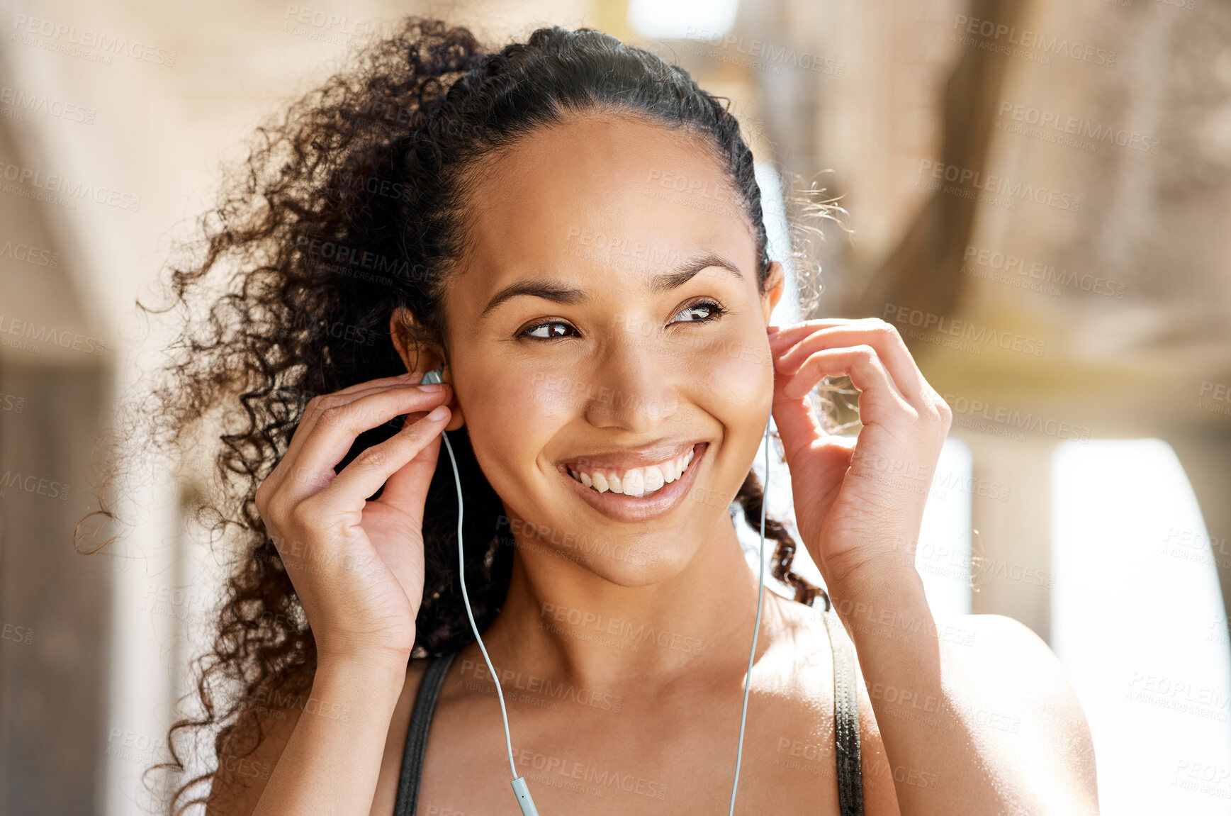 Buy stock photo Shot of an attractive young woman putting her earphones in during her outdoor workout in the city