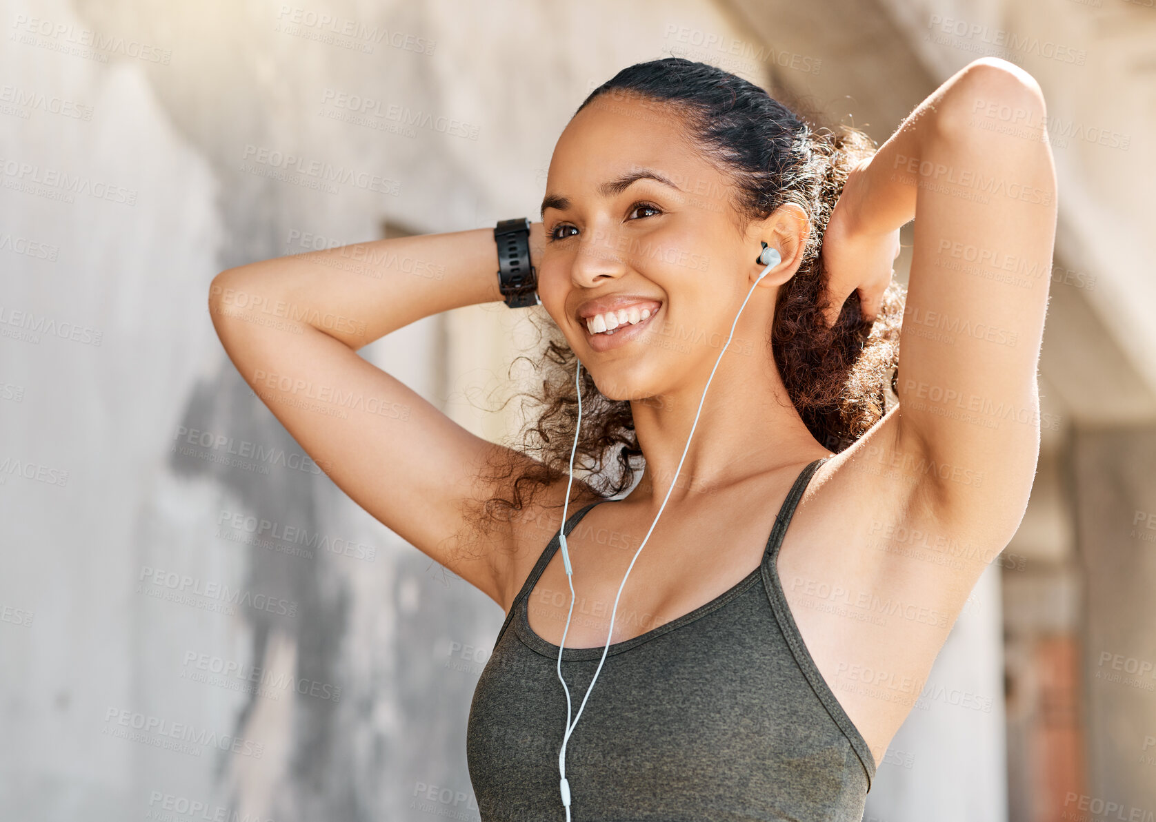 Buy stock photo Shot of an attractive young woman standing alone and listening to music through earphones during her workout in the city