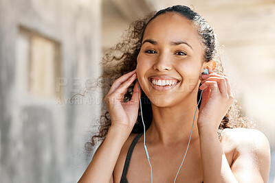 Buy stock photo Shot of an attractive young woman putting her earphones in during her outdoor workout in the city