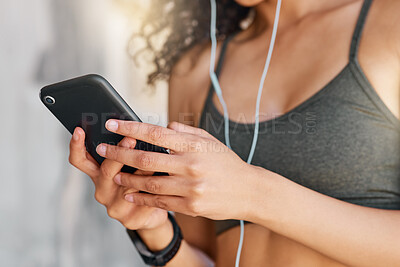 Buy stock photo Cropped shot of an unrecognisable woman standing in city and using her cellphone to listen to music during her workout