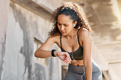 Buy stock photo Shot of an attractive young woman looking contemplative while checking her watch during her outdoor workout