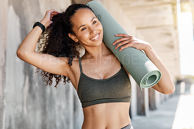 Buy stock photo Shot of an attractive young woman standing and holding a yoga mat while tying her hair during her outdoor workout