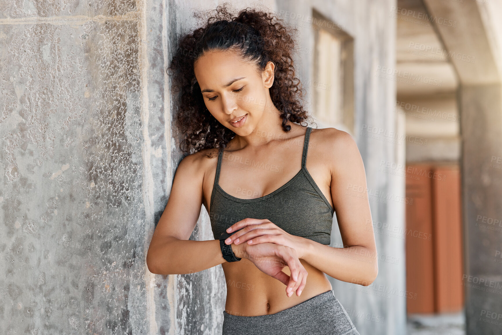 Buy stock photo Shot of an attractive young woman looking contemplative while checking her watch during her outdoor workout