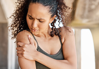 Buy stock photo Shot of an attractive young woman suffering from a shoulder injury during her outdoor workout