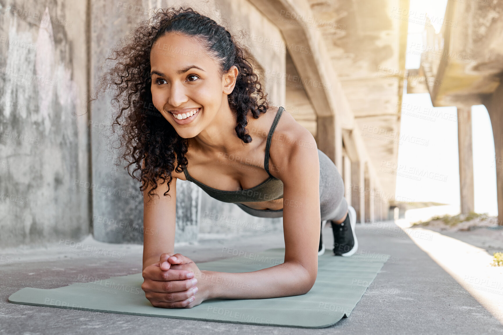 Buy stock photo Shot of an attractive young woman holding a plank pose during her outdoor workout in the city