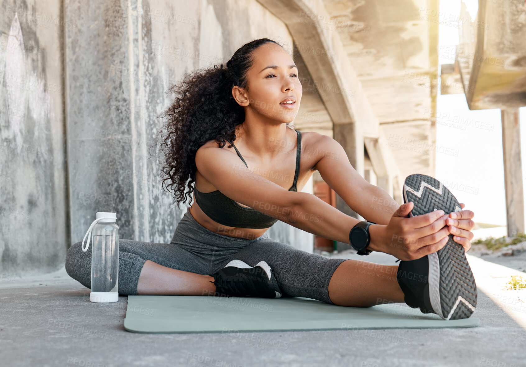 Buy stock photo Full length shot of an attractive young woman sitting alone and stretching before her outdoor workout in the city