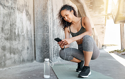 Buy stock photo Full length shot of an attractive young woman crouching down and using her cellphone during her outdoor workout