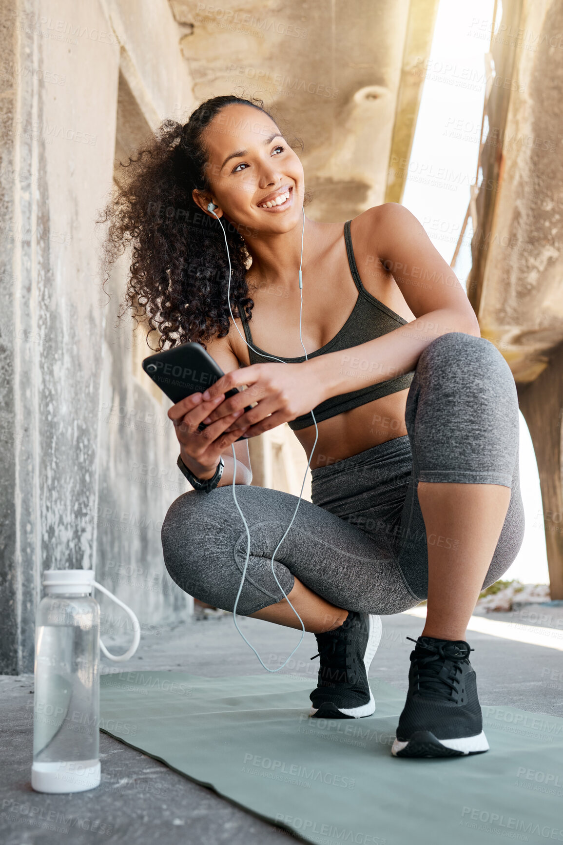 Buy stock photo Full length shot of an attractive young woman crouching down and using her cellphone during her outdoor workout