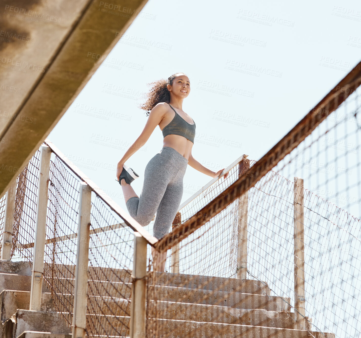 Buy stock photo Shot of an attractive young woman standing alone in the city and stretching before her outdoor workout