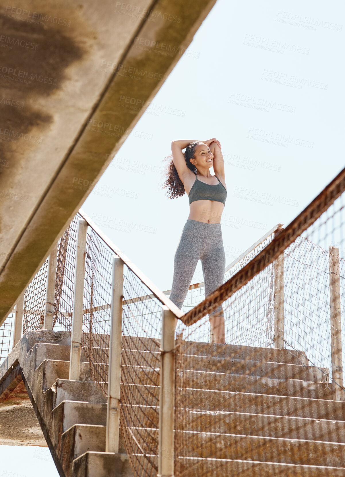 Buy stock photo Shot of an attractive young woman standing alone in the city and stretching before her outdoor workout