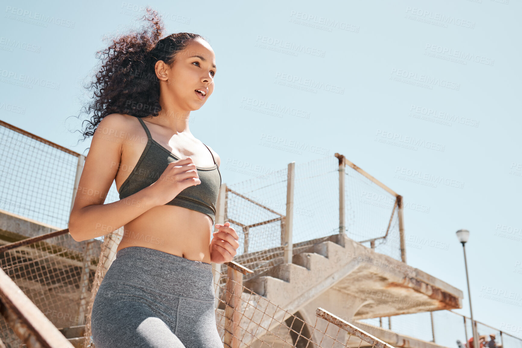 Buy stock photo Shot of an attractive young woman running down stairs during her outdoor workout in the city