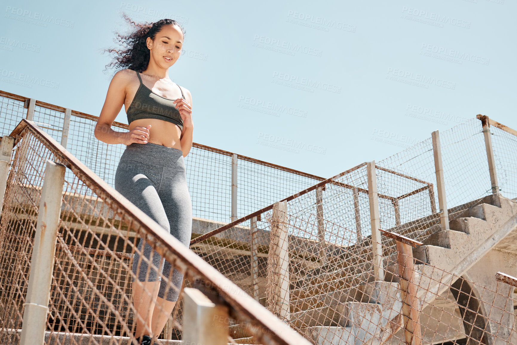 Buy stock photo Shot of an attractive young woman running down stairs during her outdoor workout in the city