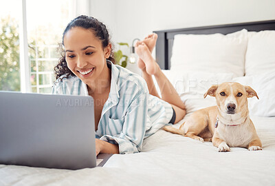 Buy stock photo Shot of a young woman using a laptop while relaxing on her bed at home