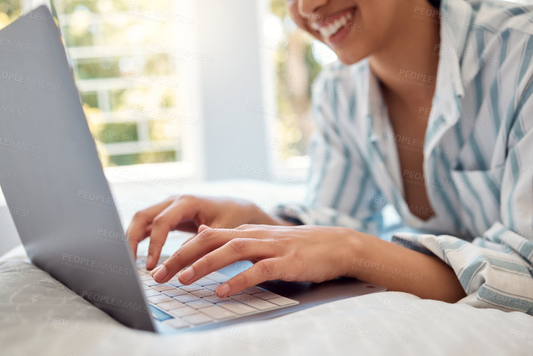 Buy stock photo Shot of an unrecognizable person using a laptop while relaxing on her bed at home